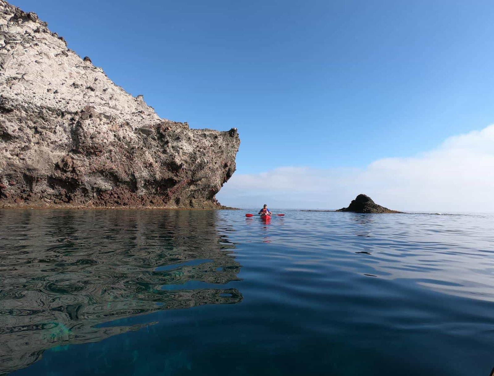 Kayakista remando en aguas en calma junto a una roca volcánica del Parque Natural de Cabo de Gata
